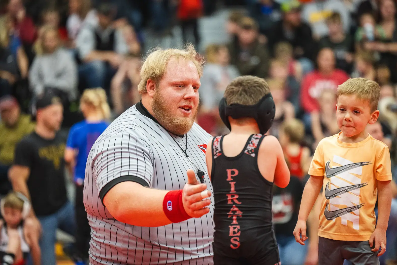 A referee encouraging two young wrestlers after their match