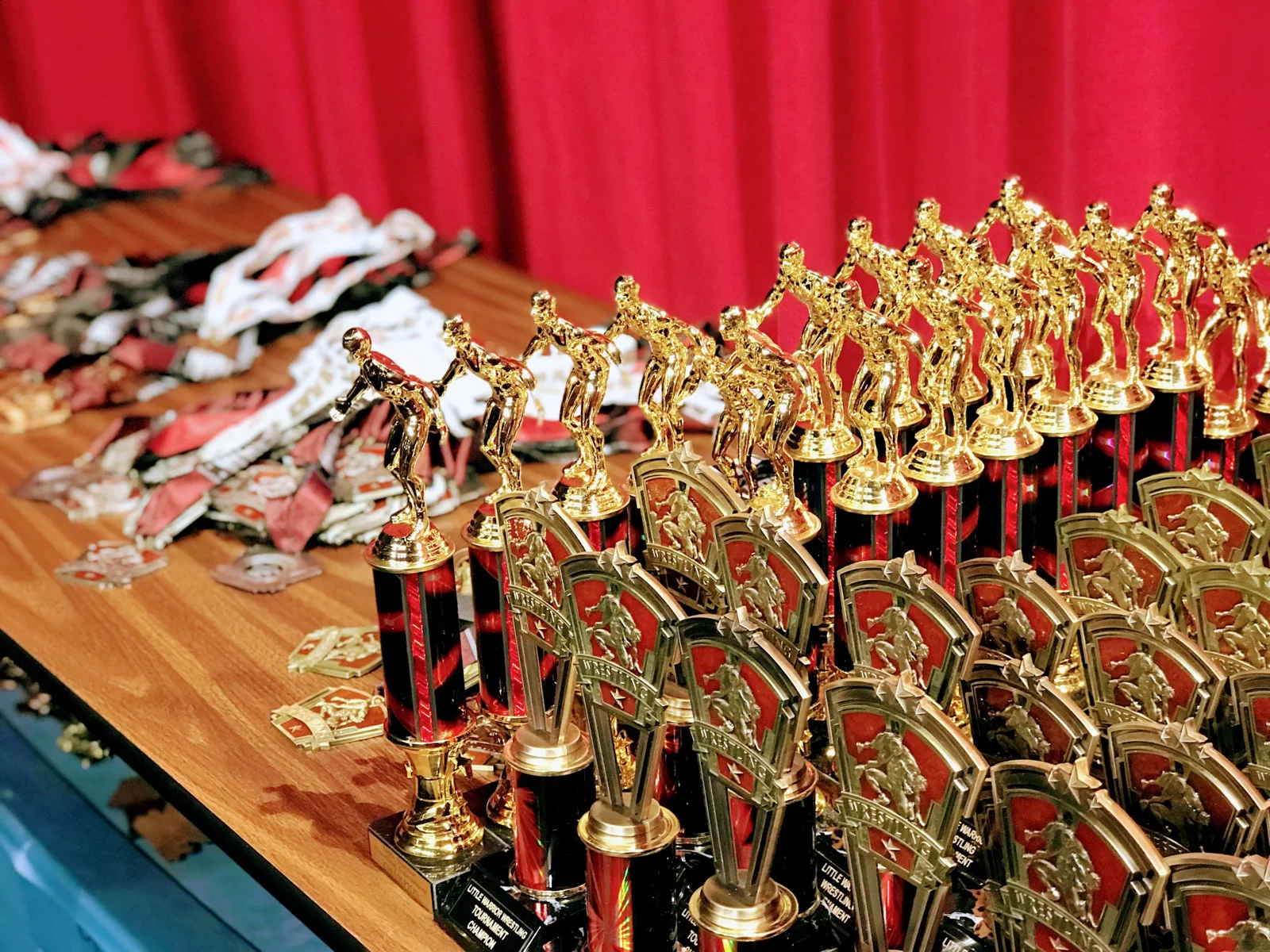 Gold wrestler trophies and medals lined up on the awards table